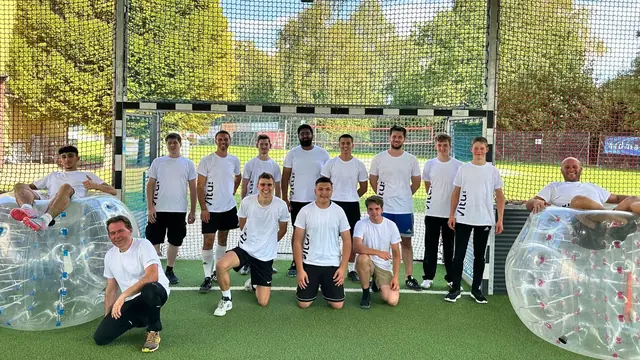 Gruppe in weißen Shirts mit Bubbles auf dem Kunstrasen