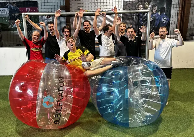 Männergruppe jubelt beim JGA mit Bubble Soccer vor dem Tor