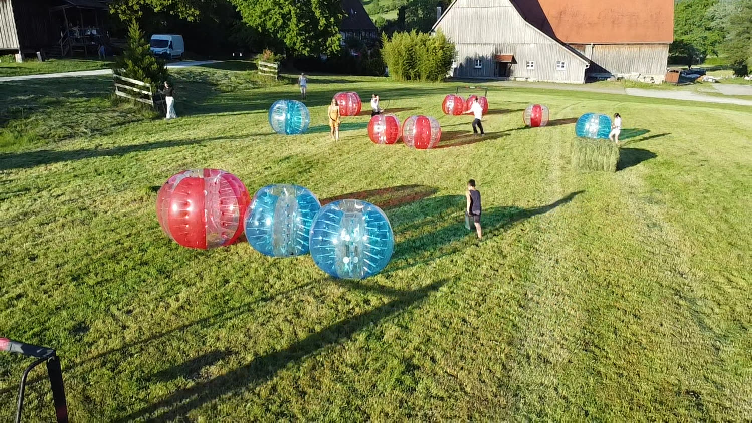 Bubble Soccer auf der Wiese einer Gemeindefreizeit – Luftaufnahme mit Scheune